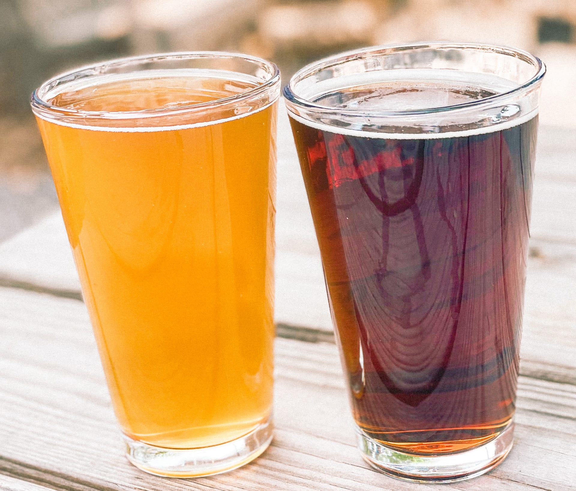 Two glasses of beer, one light golden in color the other dark amber