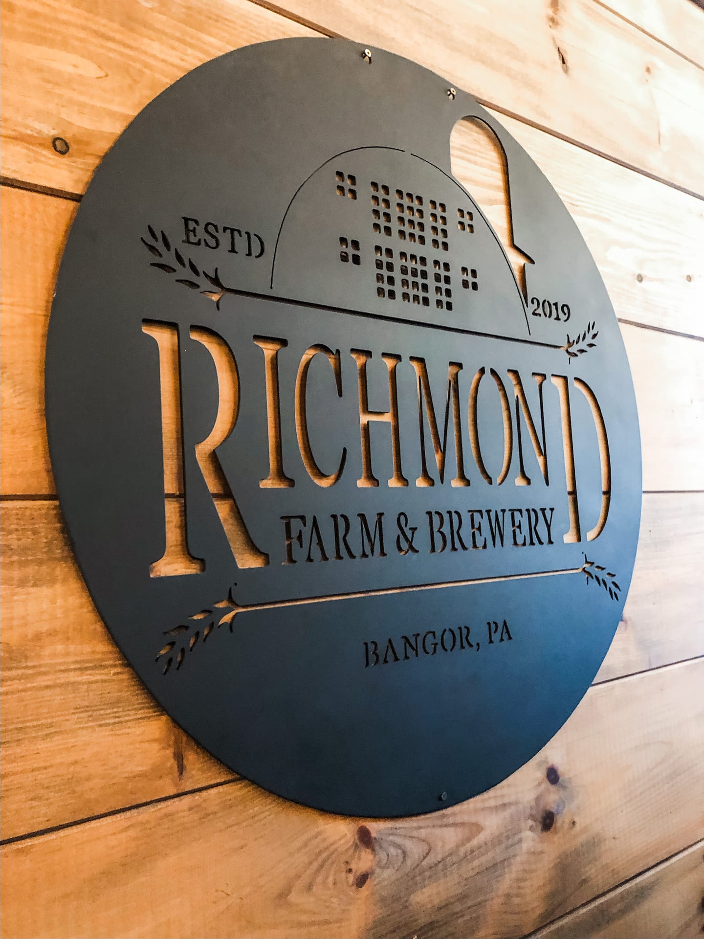 Metal circle sign that says Richmond Farm and Brewery