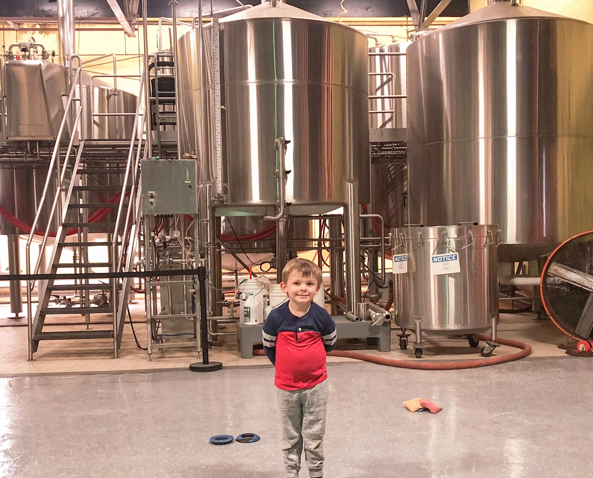 Happy boy at brewery with brew tanks in background