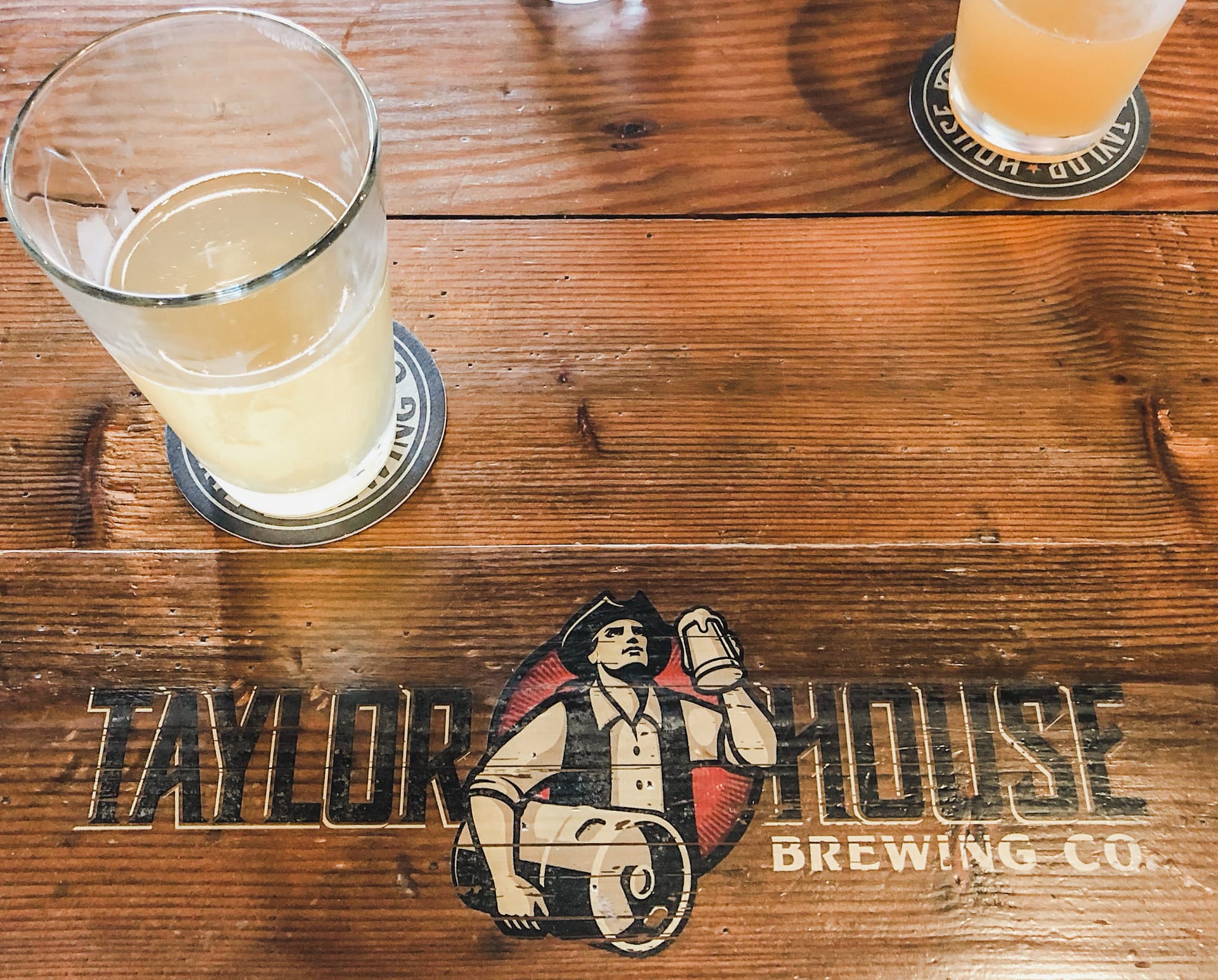 Table sign that reads Taylor House Brewing Company with a beer on the side and back