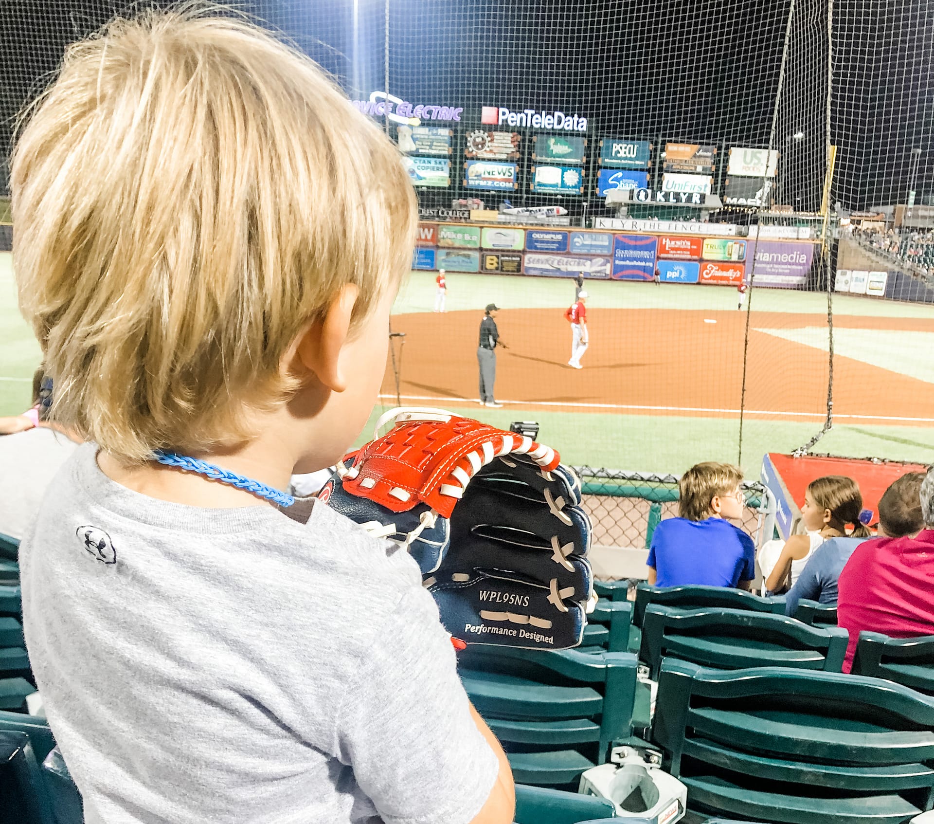 Boy watching a baseball game with his back to camera